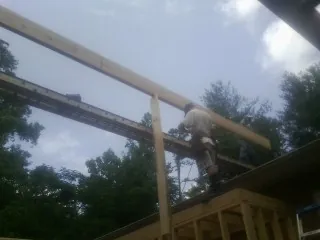 Carpenter setting a ridge beam over a new addition frame — Ice Dam Removal by Roofing Brothers in Robbins