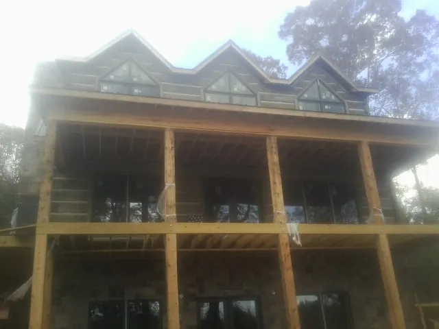Dormers and porch framing on a large log home under construction — Roof Coating work by our crew in Robbins