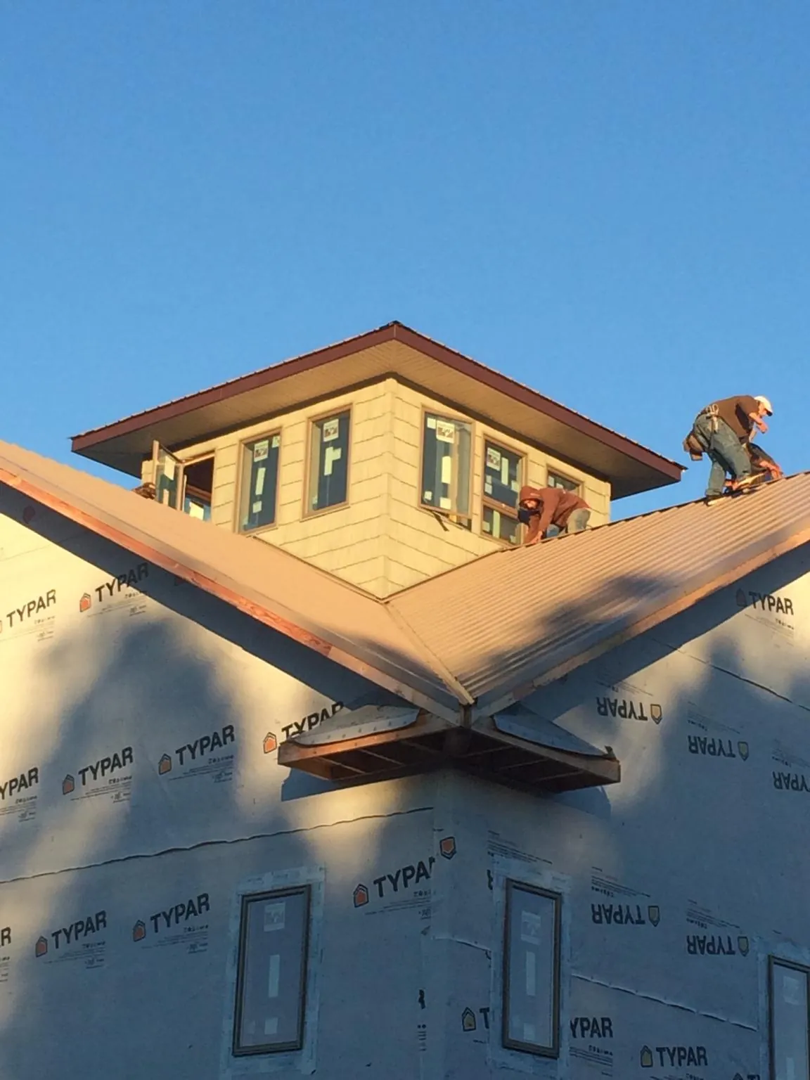 Roofers working around a rooftop cupola on a new metal roof at sunset — Roof Waterproofing in Robbins by Roofing Brothers